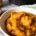 An image showing a serving of Ethiopian Spicy Pumpkin Stew, with the skillet on the back.