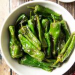 An overhead shot of a plate of fried padron peppers, straight out of the pan.