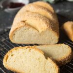 A loaf of semolina bread on a cooling rack, with a couple of slices ready for serving.