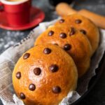 A closet shot of German chocolate buns, served in a bread basket, with an espresso and black coffee.