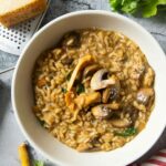 An overhead shot off a serving of mushroom risotto with some grated Parmigiano Reggiano on top.