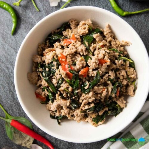 Feature image for Thai Basil Pork, showing the dish served on a plate, with fresh red and green chili around it.