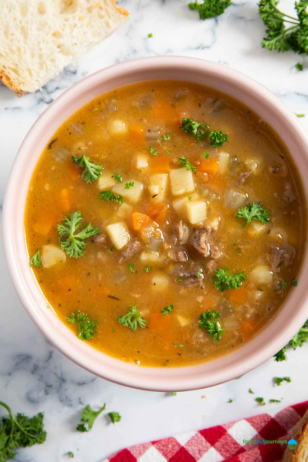 A bowl of soup with oxtail, served with bread and garnished with fresh parsley.