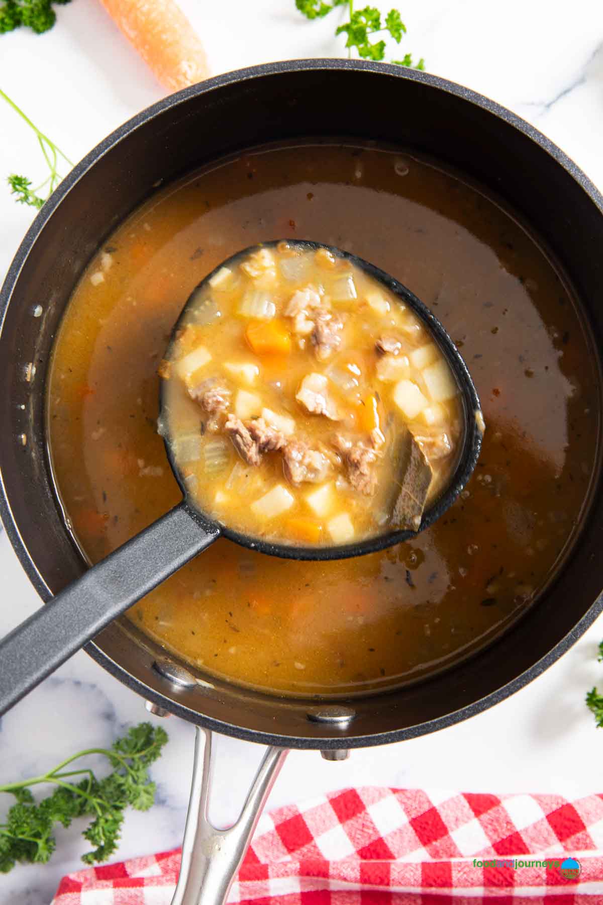 A ladle of Germ style oxtail soup, ready for transferring into bowls.