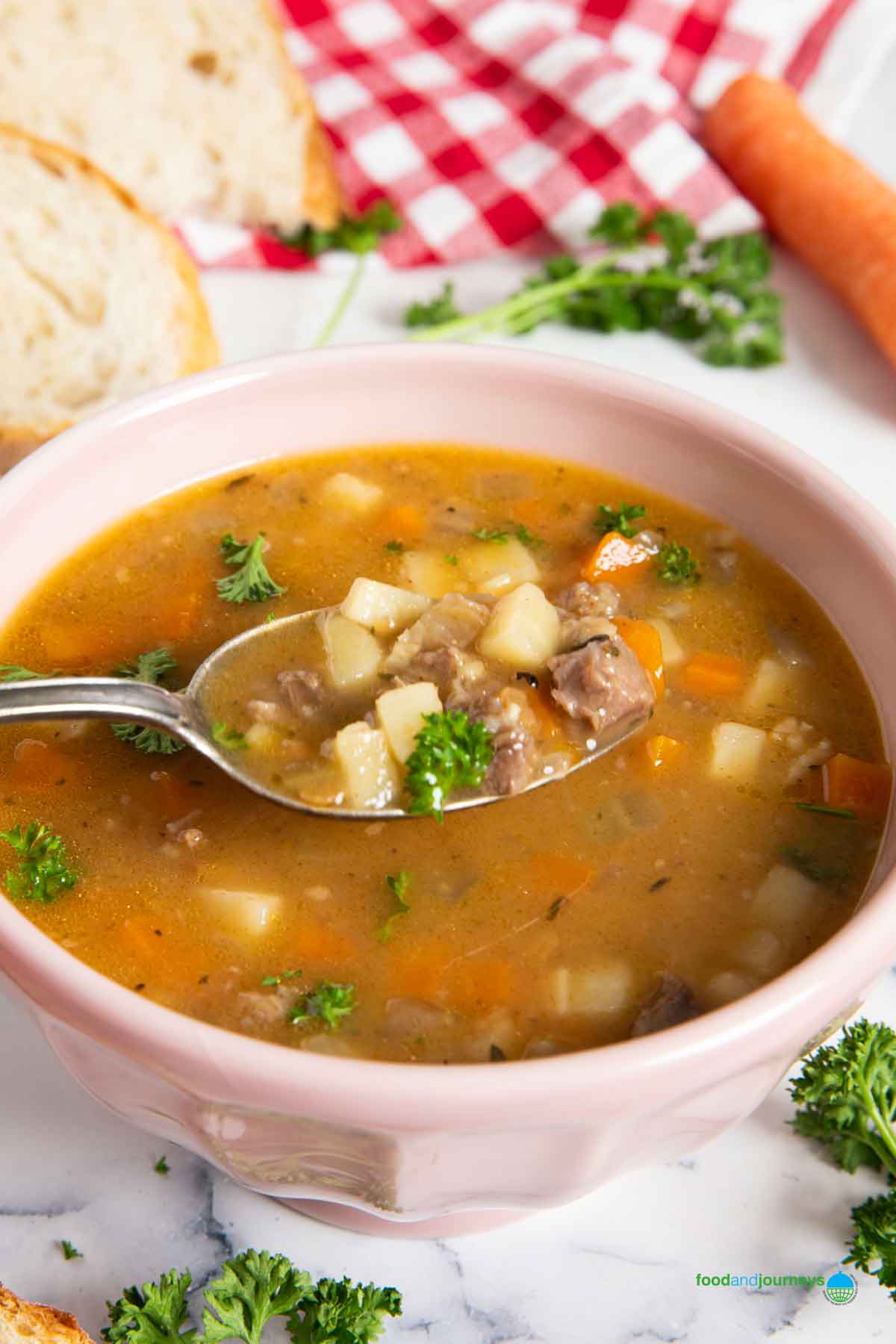 A spoonful of German style oxtail soup, highlighting the bits of meat and vegetables in it.