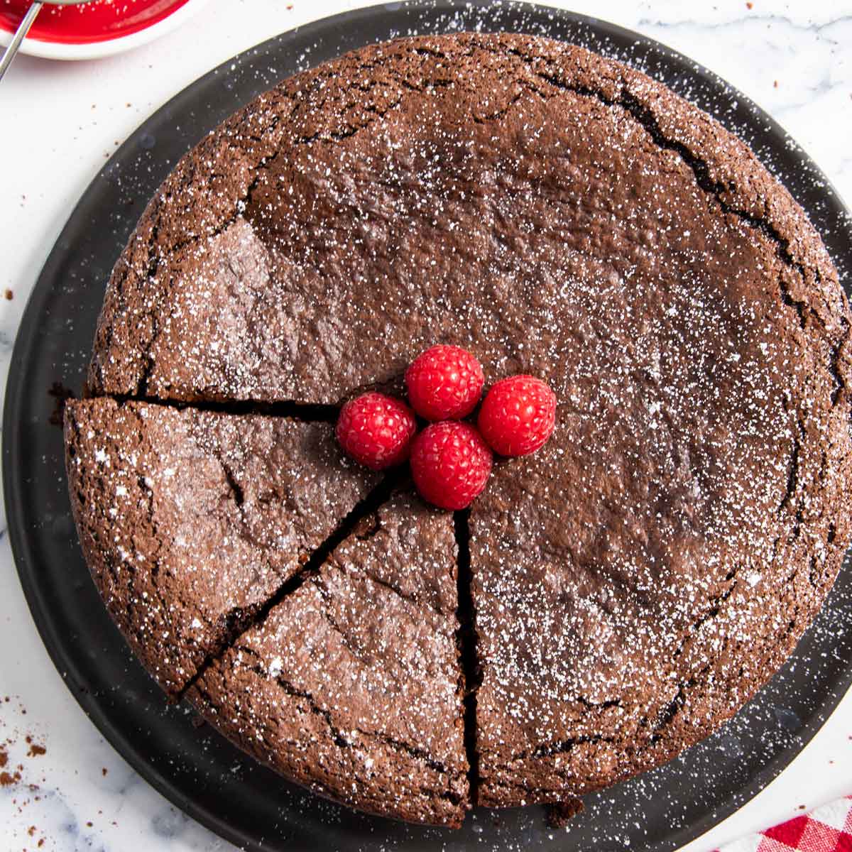 Spanish chocolate cake, sprinkled with powdered sugar, and with slices ready for serving.