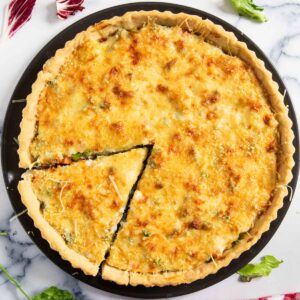 French vegetable tart on a plate, with a slice ready for serving.
