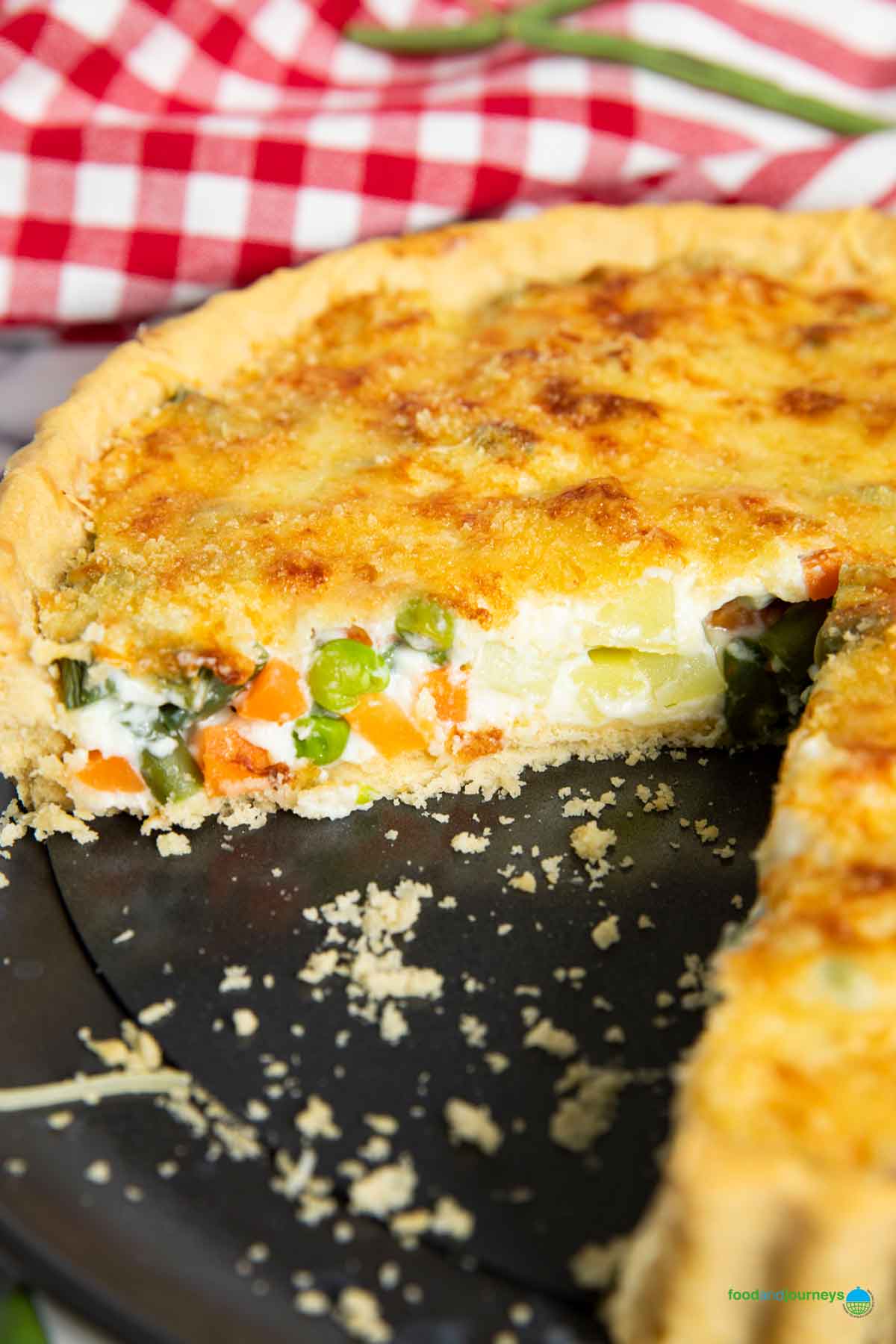 A closer shot of the inside of a French vegetable tart, showing the contrast between the creamy filling, and the crunchy pasty and cheese on top.