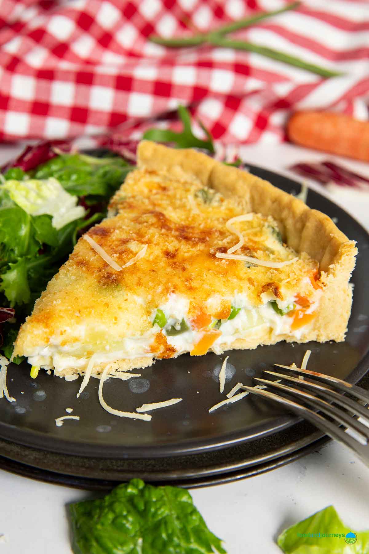A closer shot of a slice of creamy vegetable tart, highlighting the filling and bits of vegetables inside.