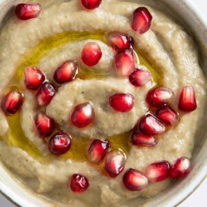 A closer shot of baba ganoush sprinkled with pomegranate seeds, highlighting its smooth texture.