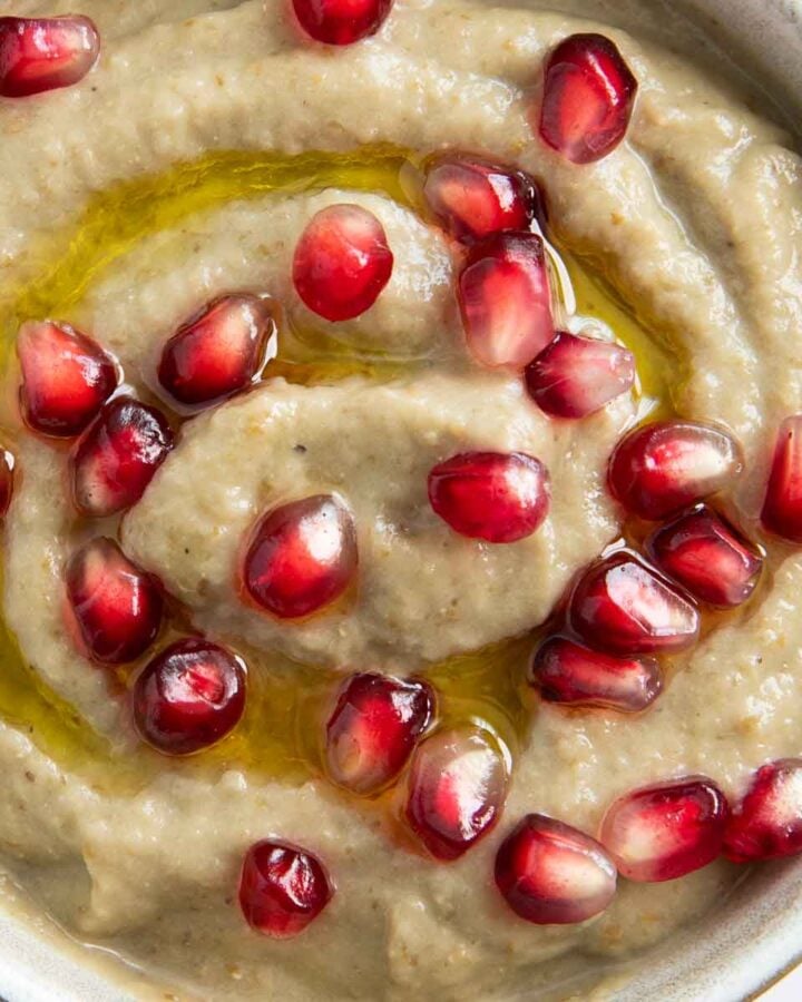 A closer shot of baba ganoush sprinkled with pomegranate seeds, highlighting its smooth texture.