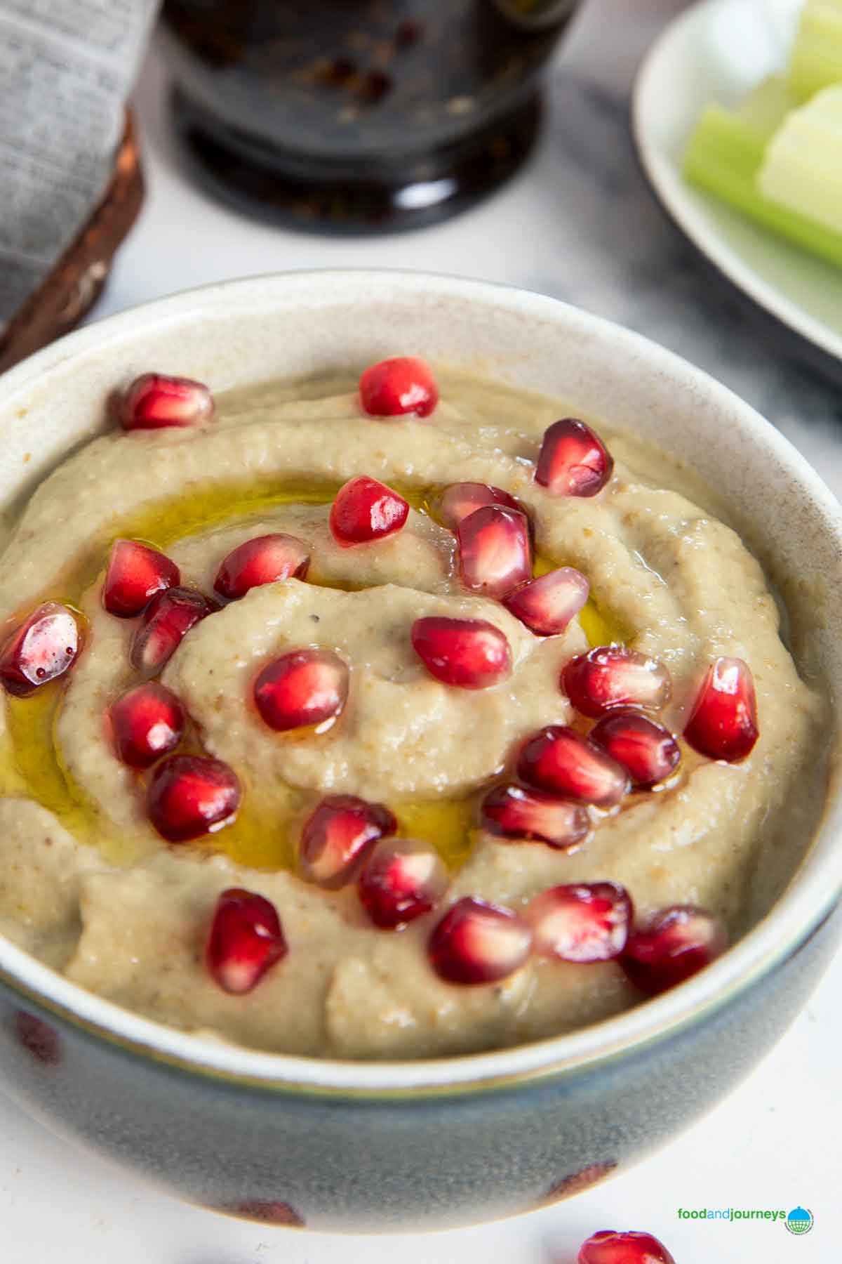 A bowl of traditional Lebanese baba ganoush, with olive oil and fresh celery sticks next to it.