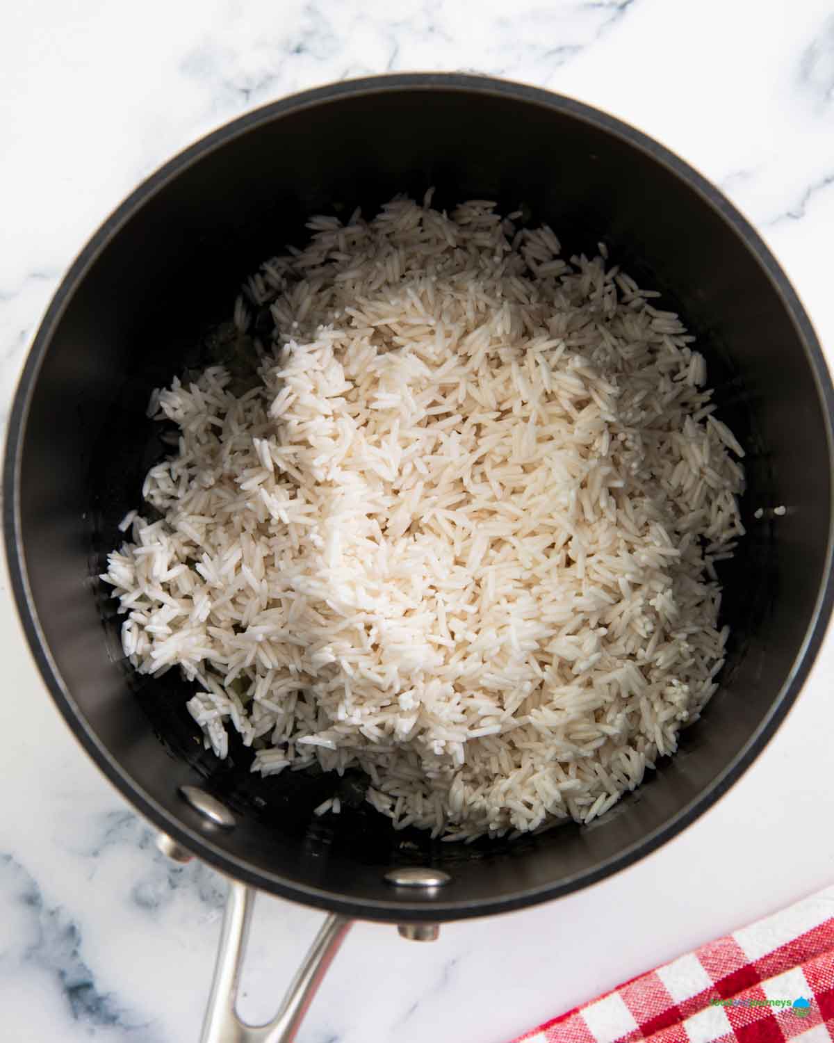 Adding the rinsed rice before combining it with the yellow stock, with saffron.