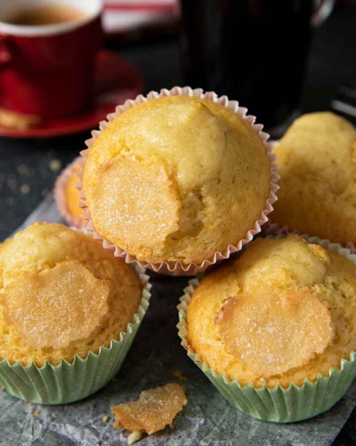 Freshly baked Spanish muffins, served with a cup of espresso in the background.