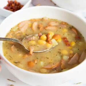 A spoonful of yellow peas, potatoes, bacon and sausage, the main ingredients for classic pea soup from Germany.