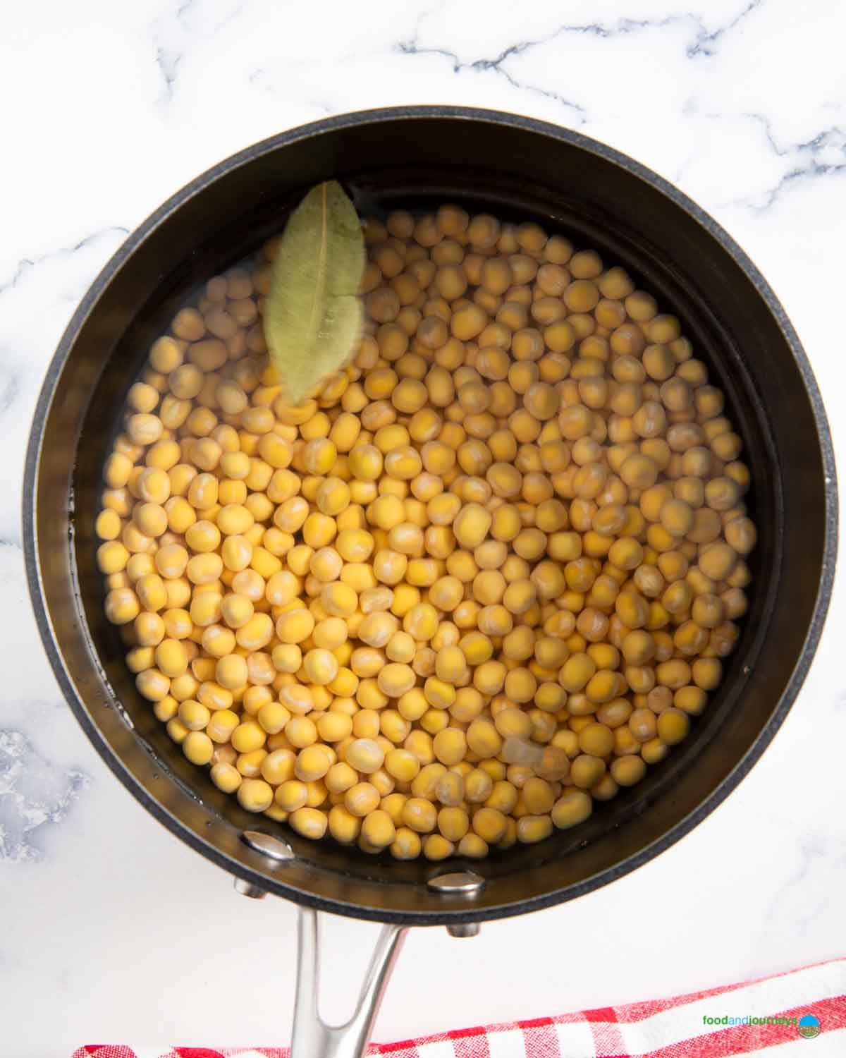 Dried yellow peas soaking in water with a bay leaf in a saucepan, preparing the base for traditional German pea soup (Erbsensuppe).