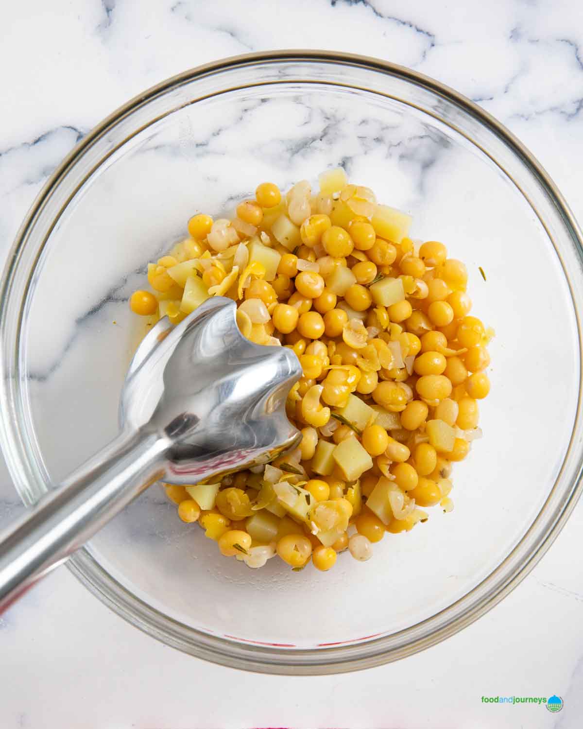 Using an immersion blender to puree a portion of the yellow peas and potatoes, before adding it back into the pan for erbsensuppe.
