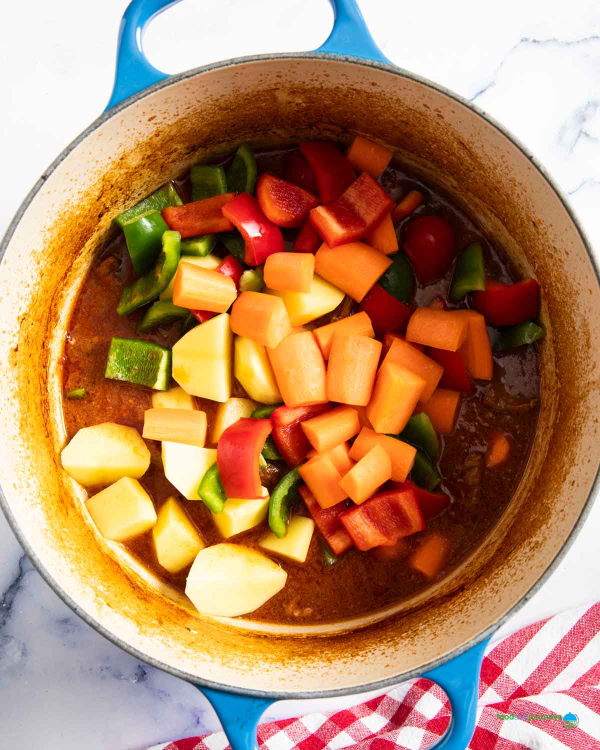 Chopped carrots, potatoes and bell peppers are added to the pot of kaldereta, once the beef has softened.