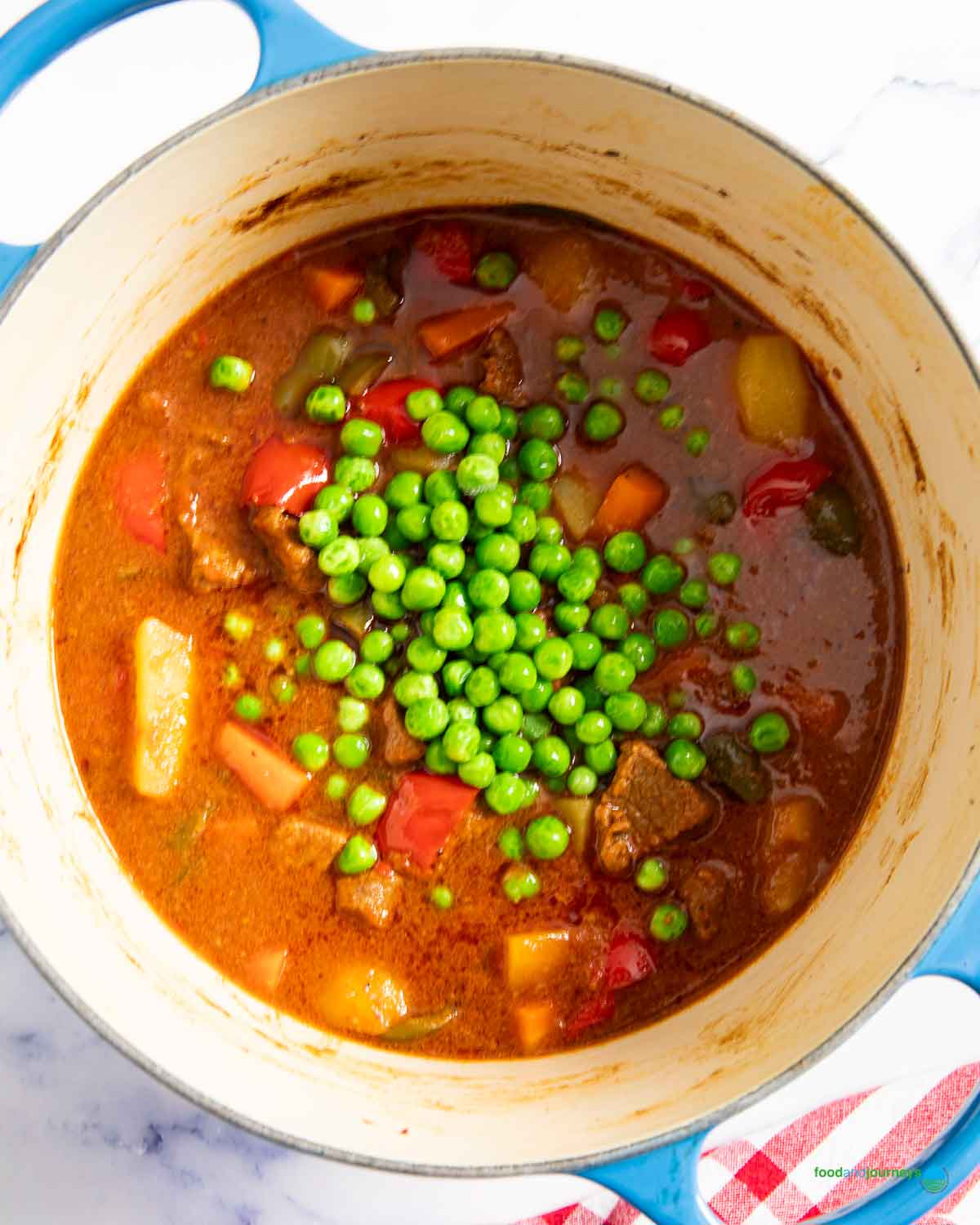 Adding the green peas in the last part of cooking the Filipino kaldereta with beef.