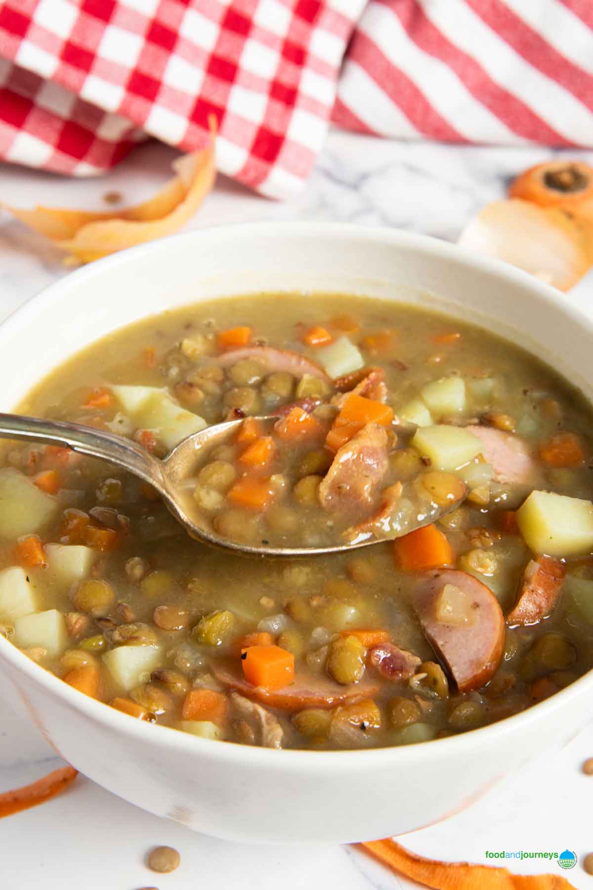 A spoonful of linsensuppe, highlighting the lentils, vegetables and bacon bits in every bite.