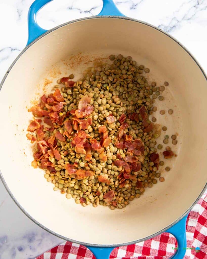 Dried green lentils are added to the base ingredients, before pouring the stock for the soup.