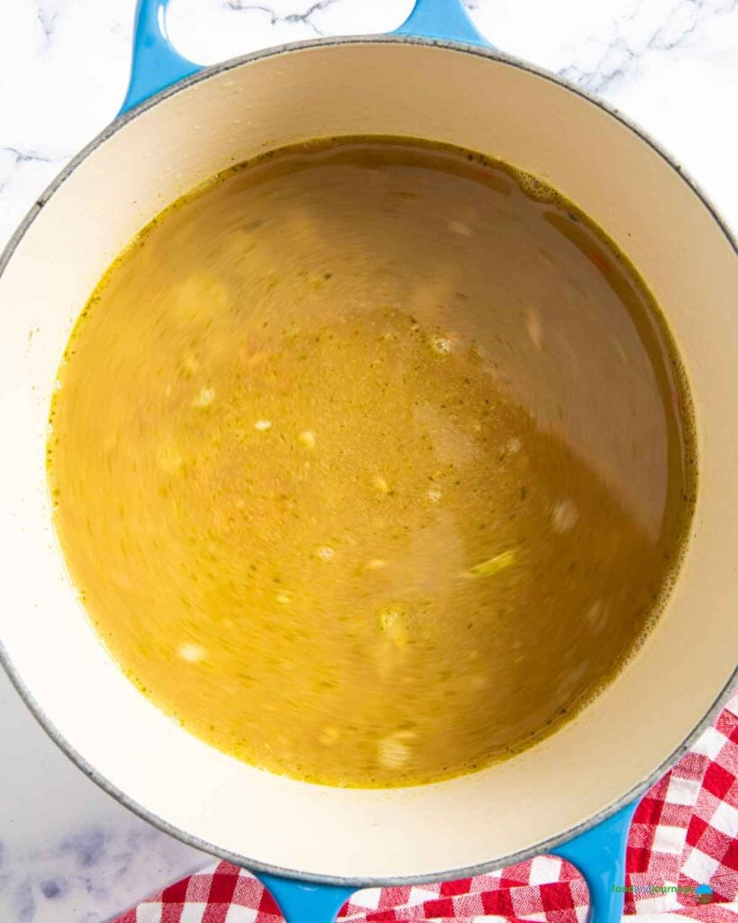 Pouring stock and simmering until the lentils are tender.