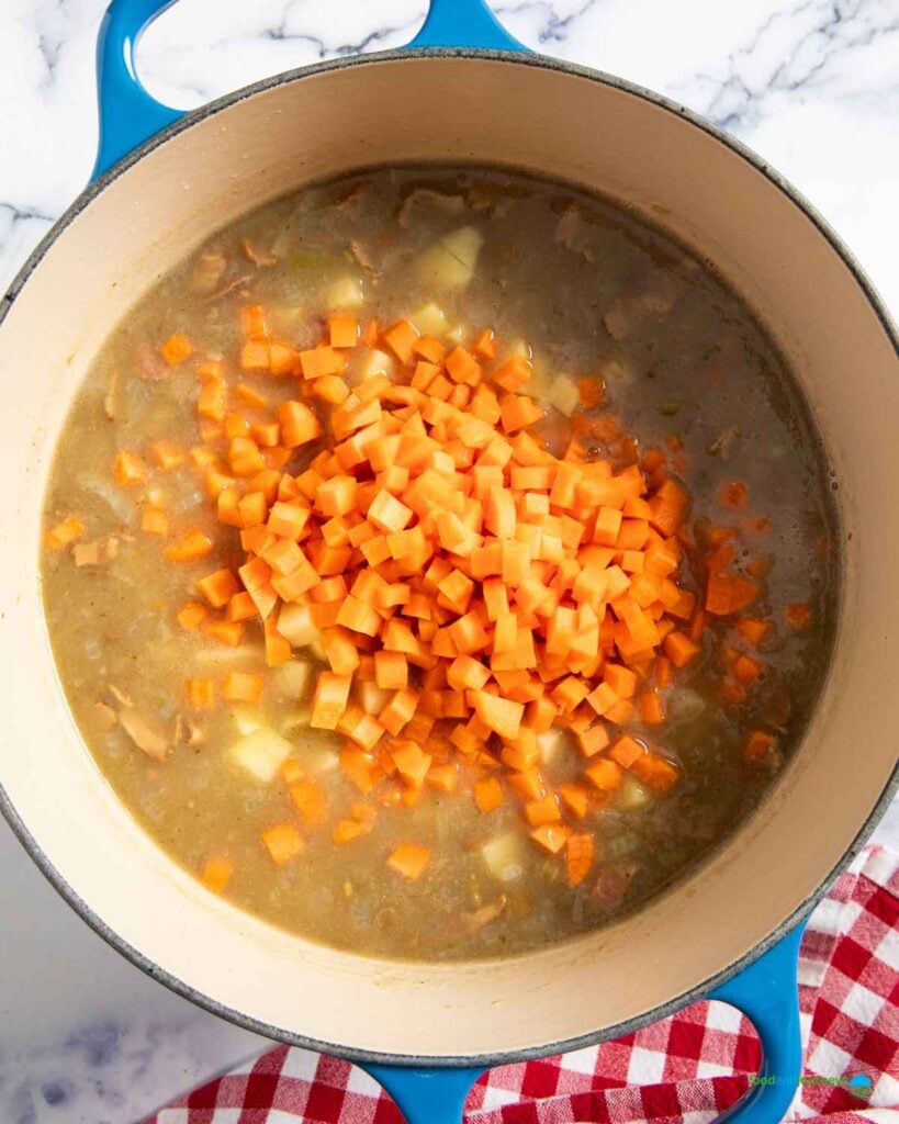 Adding carrots and potatoes into the softened lentils, while continuing to simmer the soup.