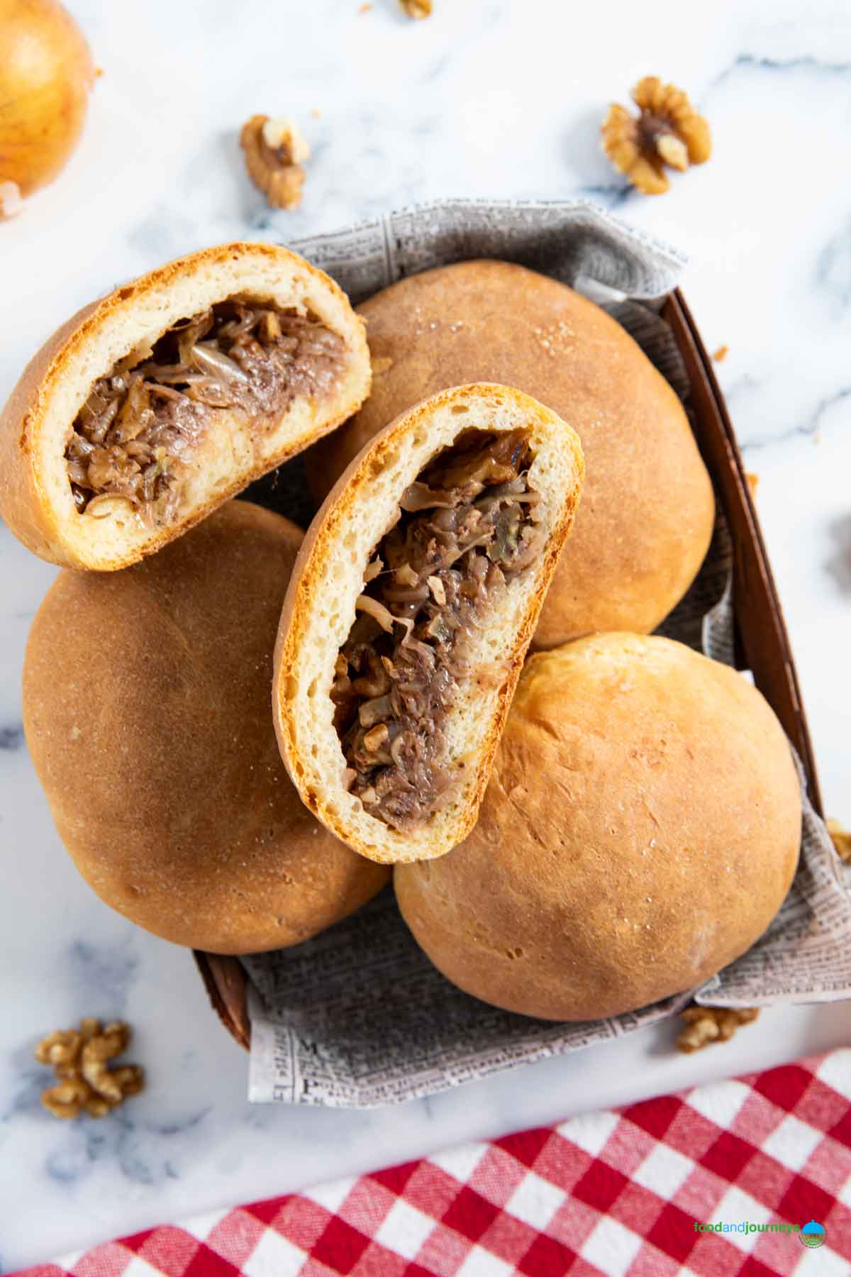 A Lebanese onion and walnut bread cut into half, to show the filling inside, with whole walnuts in the background.